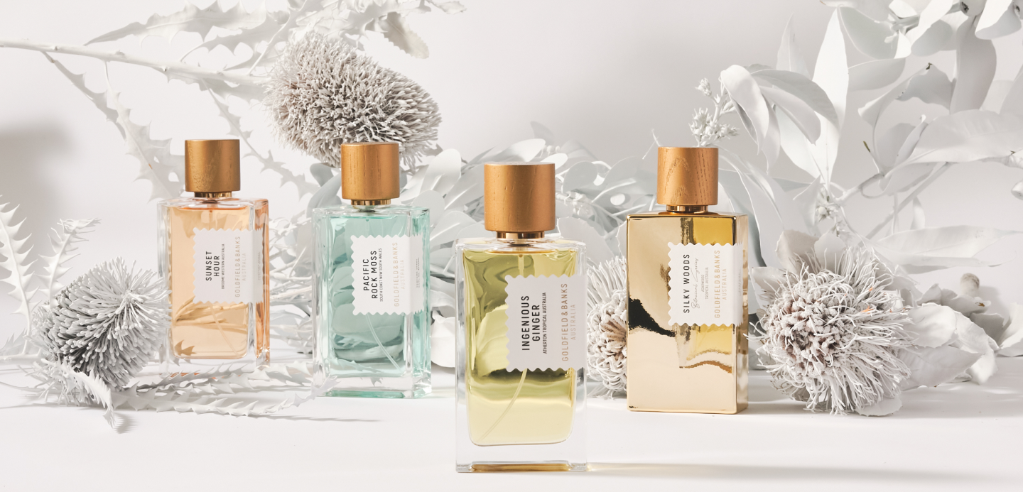 Luxury perfume bottles arranged in a clean studio setting with soft botanical elements in the background